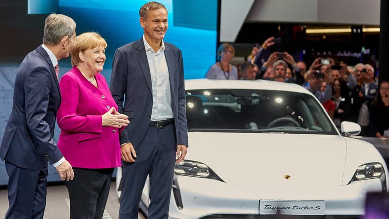 Bundeskanzlerin Angela Merkel (CDU), Oliver Blume (r), Vorstandsvorsitzender von Porsche, und VDA-Präsident Bernhard Mattes: Am Porsche-Stand der IAA 2019 informiert sich die Kanzlerin über den Elektro-Sportwagen Taycan Turbo S.