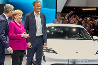 Bundeskanzlerin Angela Merkel (CDU), Oliver Blume (r), Vorstandsvorsitzender von Porsche, und VDA-Präsident Bernhard Mattes: Am Porsche-Stand der IAA 2019 informiert sich die Kanzlerin über den Elektro-Sportwagen Taycan Turbo S.