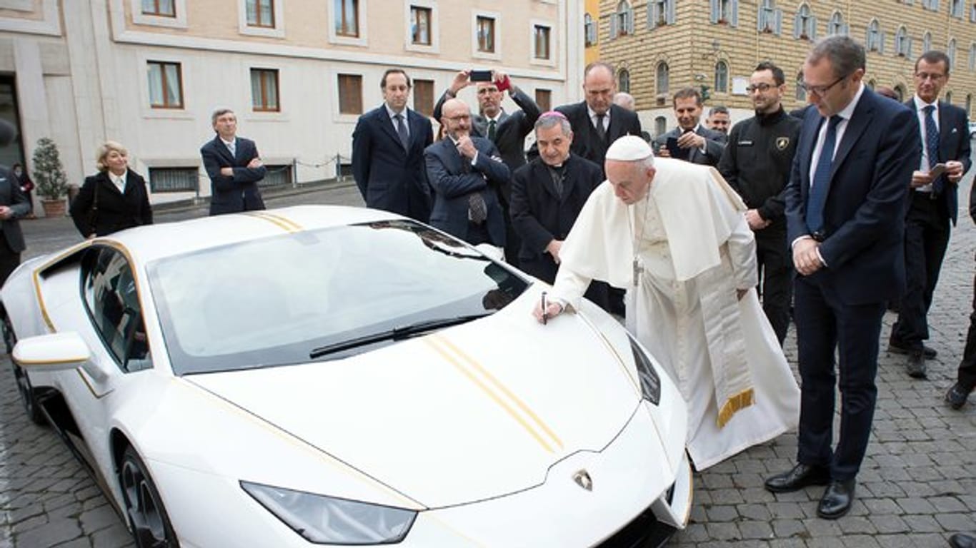 Papst Franziskus signiert den weißen Lamborghini, der ihm vom italienischen Sportwagenhersteller geschenkt wurde.