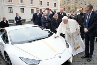 Papst Franziskus signiert den weißen Lamborghini, der ihm vom italienischen Sportwagenhersteller geschenkt wurde.