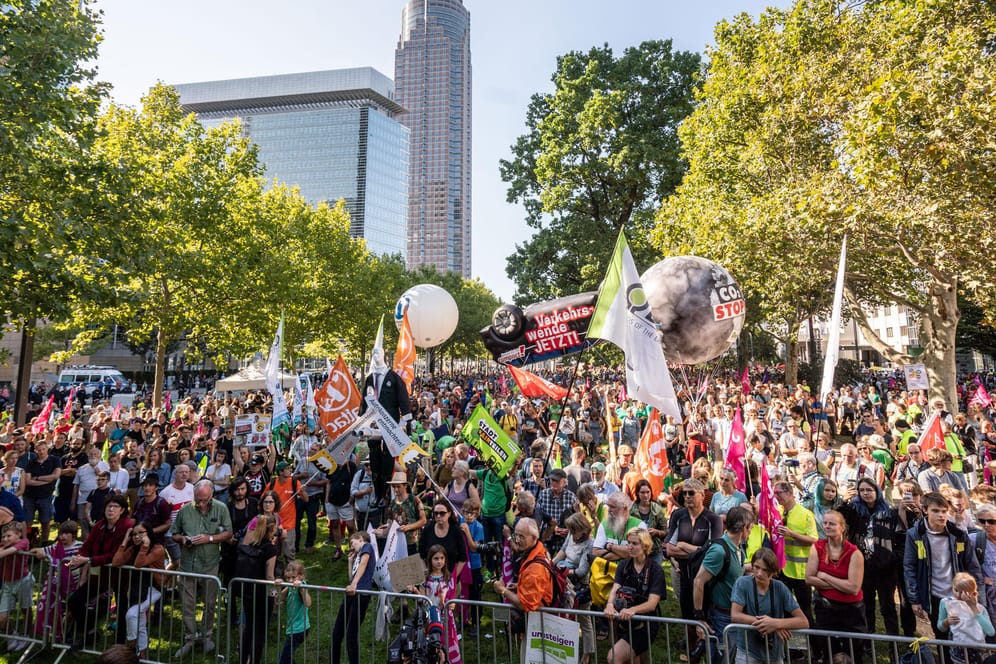 Teilnehmer einer Kundgebung stehen mit Fahnen gegenüber des Messeländes in Frankfurt: Tausende Menschen demonstrieren am ersten Publikumstag der IAA gegen die Automobilindustrie.