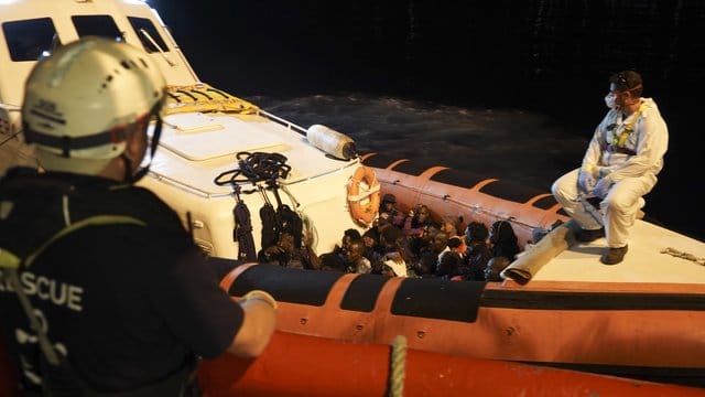 Migranten sitzen in einem Boot der italienischen Küstenwache, nachdem sie von Bord des Rettungsschiffs "Ocean Viking" gegangen sind. Migranten sitzen in einem Boot der italienischen Küstenwache, nachdem sie von Bord des Rettungsschiffs "Ocean Viking" gegangen sind.