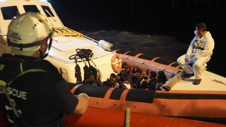 Migranten sitzen in einem Boot der italienischen Küstenwache, nachdem sie von Bord des Rettungsschiffs "Ocean Viking" gegangen sind.