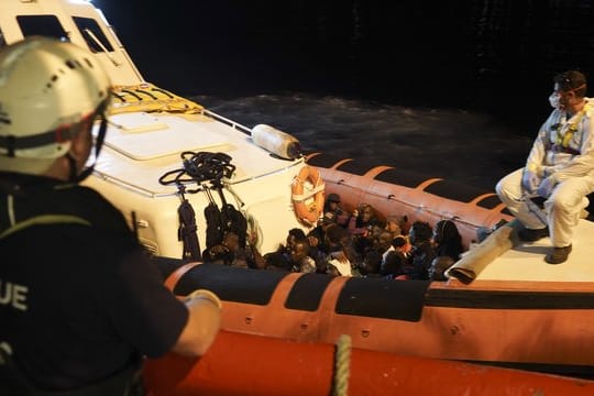Migranten sitzen in einem Boot der italienischen Küstenwache, nachdem sie von Bord des Rettungsschiffs "Ocean Viking" gegangen sind.