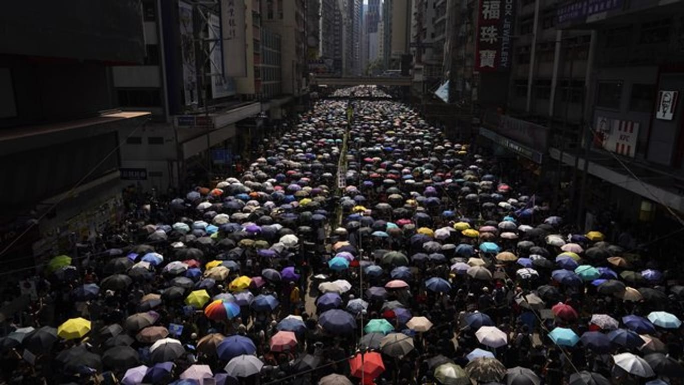 Tausende Hongkonger ziehen mit Regenschirmen über eine Straße.