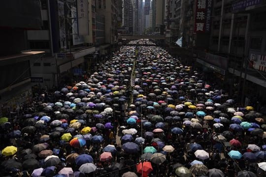 Tausende Hongkonger ziehen mit Regenschirmen über eine Straße.