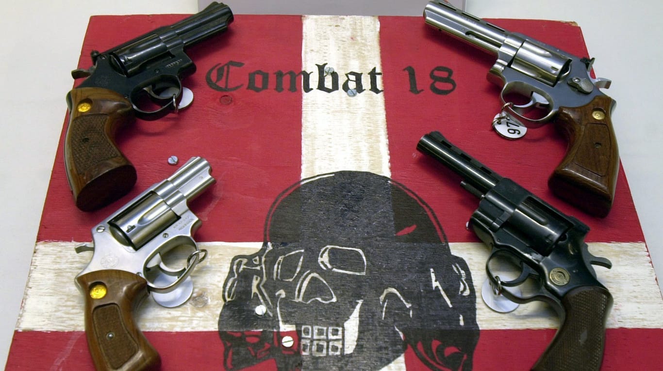 Sichergestellte Waffen und ein Schild der Neonazi-Gruppe "Combat 18" liegen im Jahr 2002 im schleswig-holsteinischen Landeskriminalamt (LKA). Im Zuge einer groß angelegten Aktion hatte die Polizei die Gruppierung "Combat 18" in Norddeutschland zerschlagen.