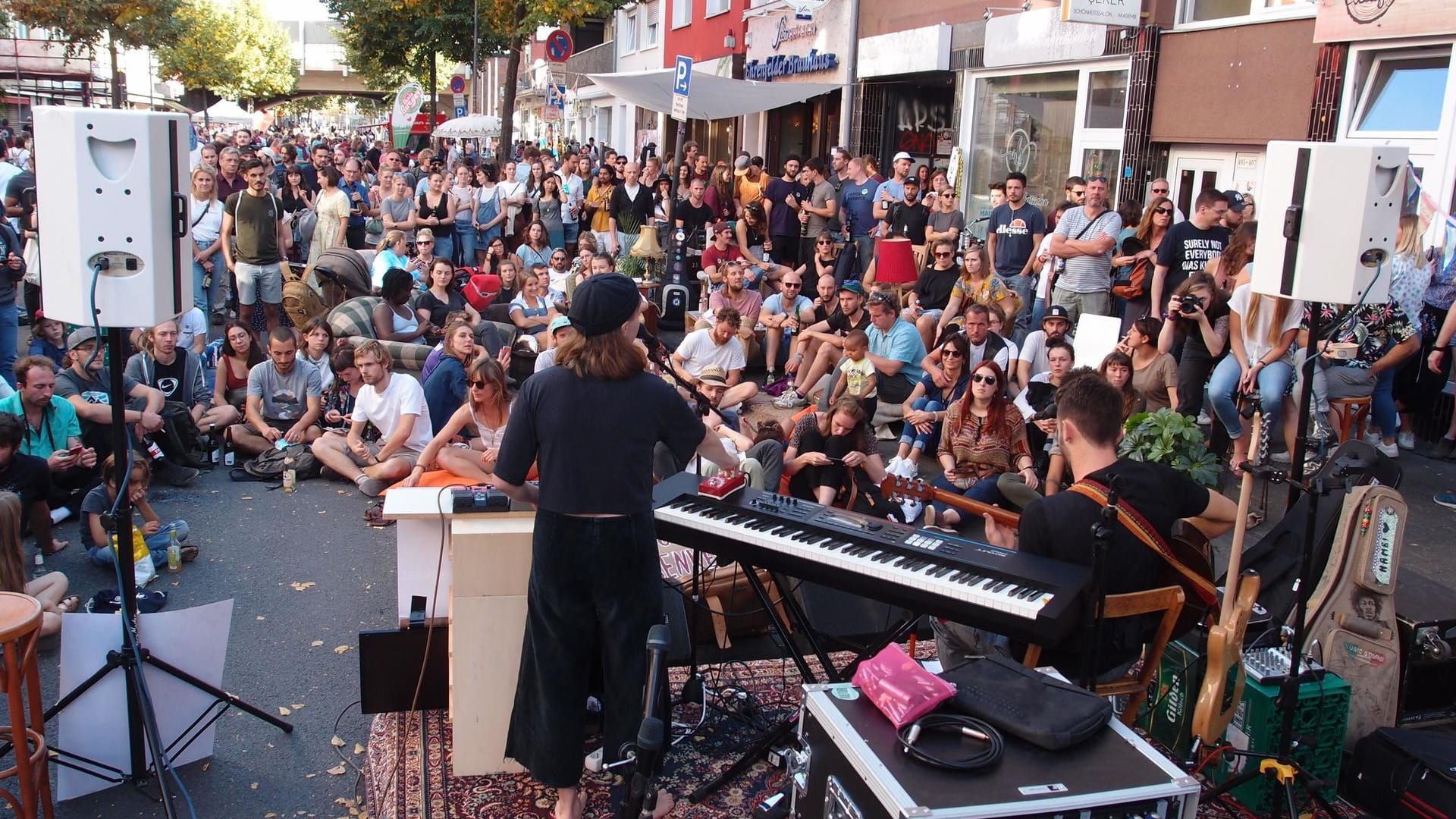 Menschen lauschen einer Musikerin in Köln: Beim "Tag des guten Lebens" kamen viele Kölner zusammen und feierten das Beisammensein.