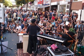 Menschen lauschen einer Musikerin in Köln: Beim "Tag des guten Lebens" kamen viele Kölner zusammen und feierten das Beisammensein.