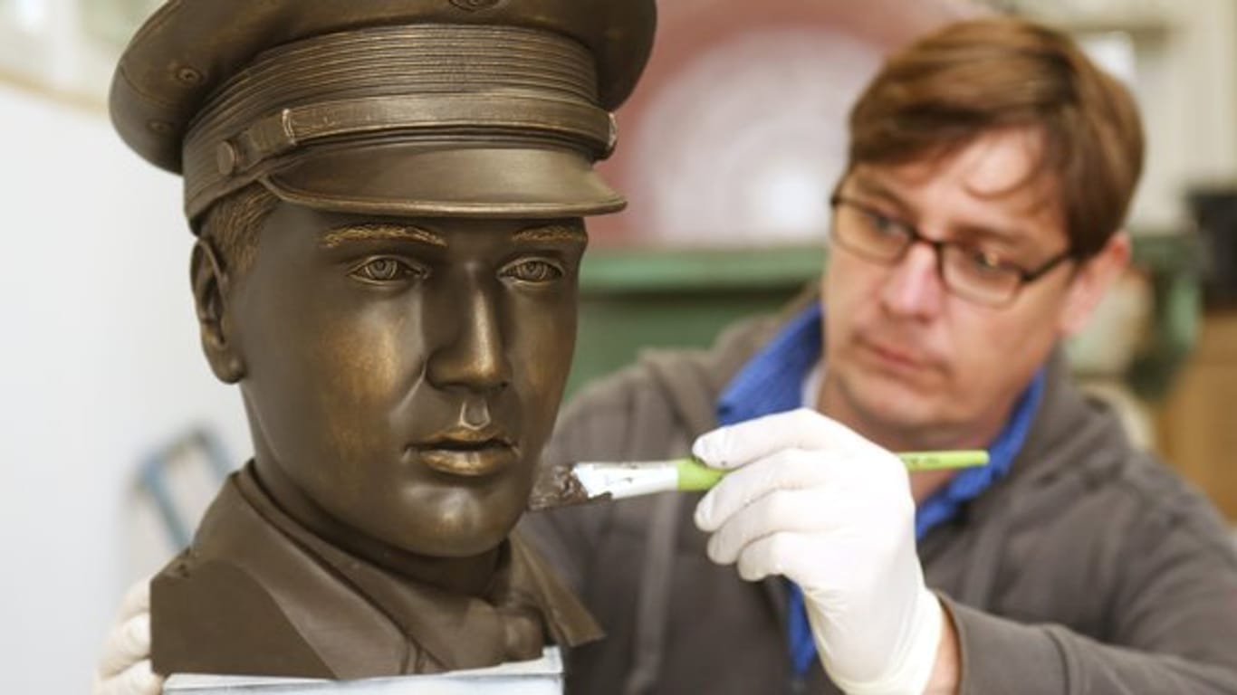 Der Techniker Michael Lenz streicht dem Prototypen des 3D-Kopfes Bronzefarbe auf.