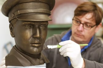 Der Techniker Michael Lenz streicht dem Prototypen des 3D-Kopfes Bronzefarbe auf.