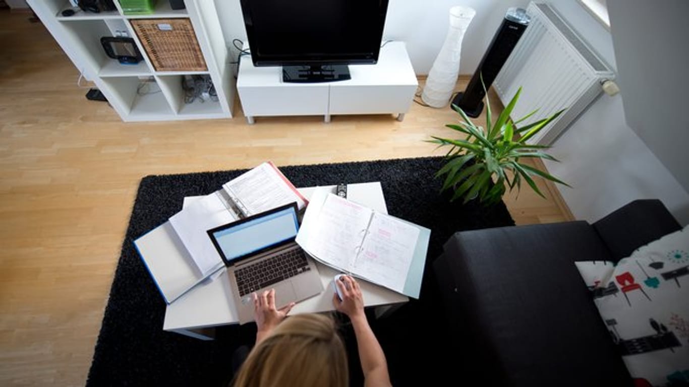 Zu Hause statt im Büro: Eine Frau arbeitet in einem Wohnzimmer an einem Laptop.