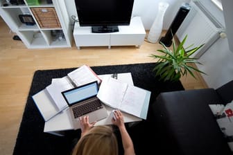 Zu Hause statt im Büro: Eine Frau arbeitet in einem Wohnzimmer an einem Laptop.
