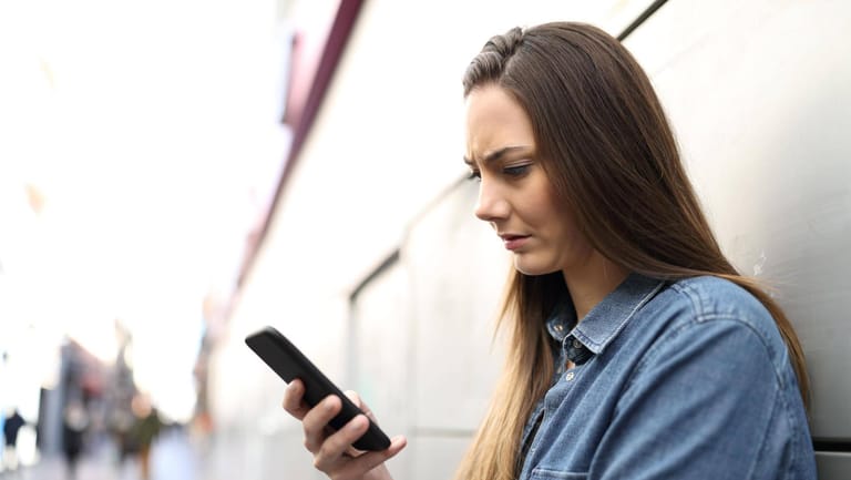 Eine Frau schaut auf ihr Smartphone: Tauchen auf der Mobilfunkrechnung nicht nachvollziehbare Posten auf, sollte man widersprechen.