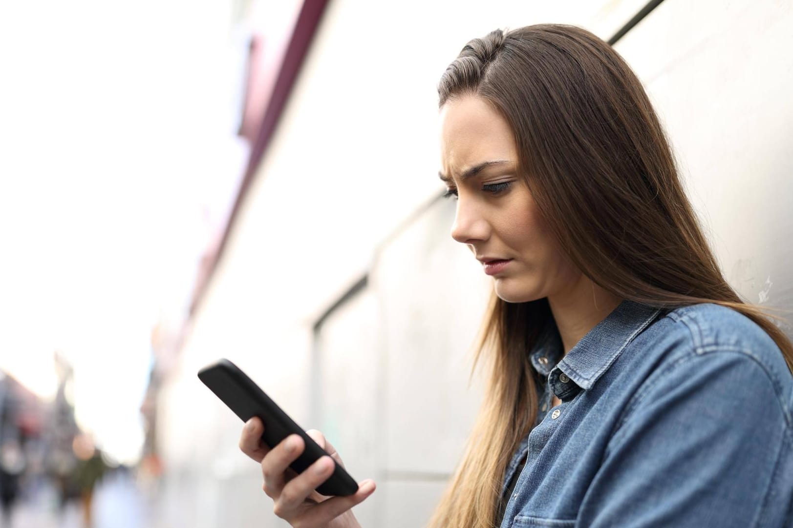 Eine Frau schaut auf ihr Smartphone: Tauchen auf der Mobilfunkrechnung nicht nachvollziehbare Posten auf, sollte man widersprechen.