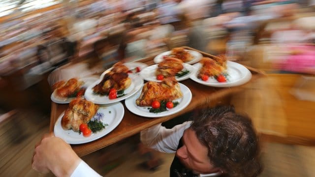 Diät geht anders: Kellner auf dem Oktoberfest mit einem Tablett Hendl (Hähnchen).