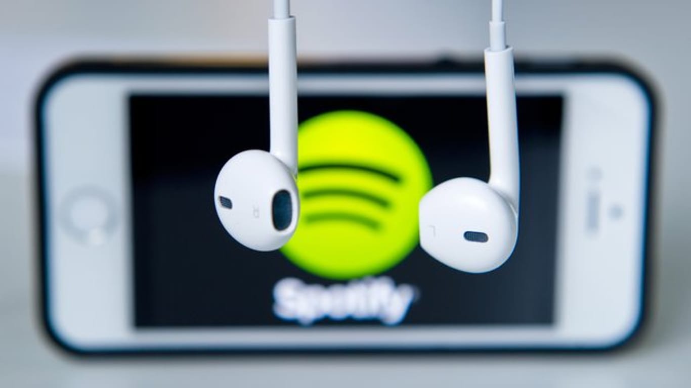 Kopfhörer vor einem Smartphone mit dem Spotify-Logo: Der Streamingdienst will in Zukunft prüfen, ob die Adressangaben korrekt sind.