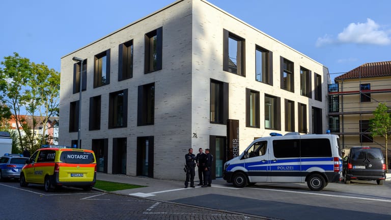 Wismar: Polizisten und ein Notarztwagen stehen vor dem Landratsamt, in dem ein Mann ein Kind als Druckmittel einsetzt.