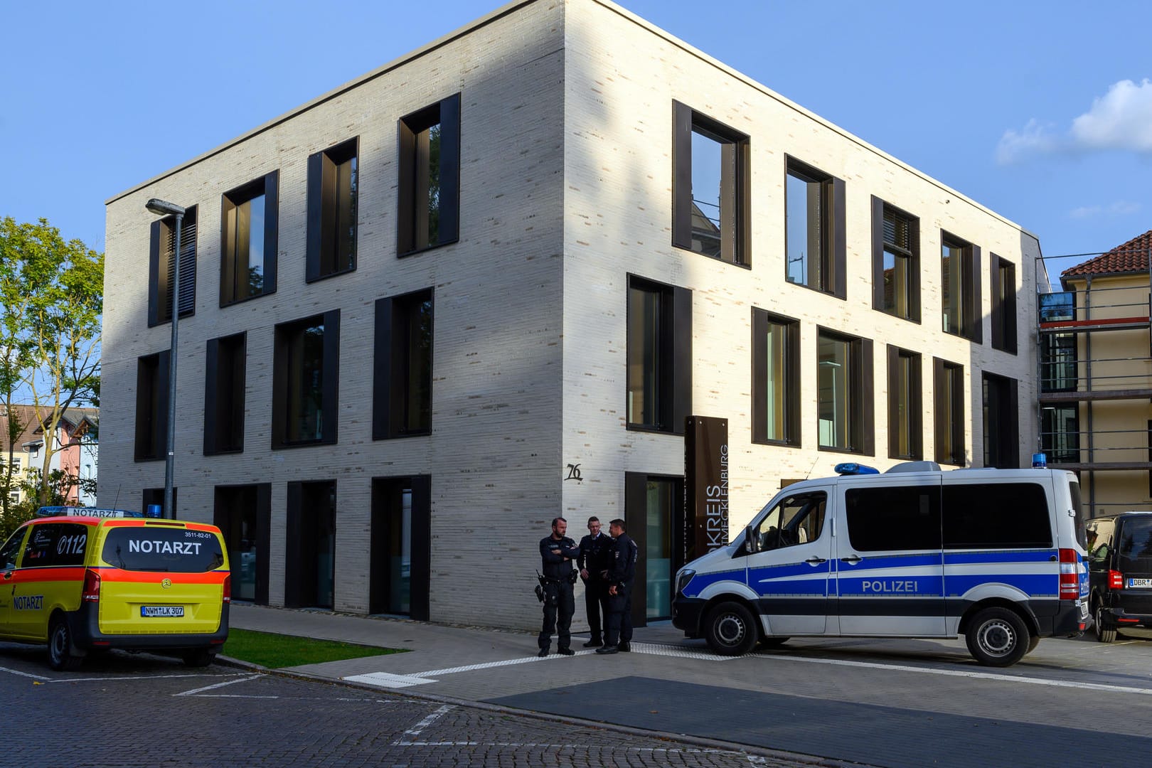 Wismar: Polizisten und ein Notarztwagen stehen vor dem Landratsamt, in dem ein Mann ein Kind als Druckmittel einsetzt.