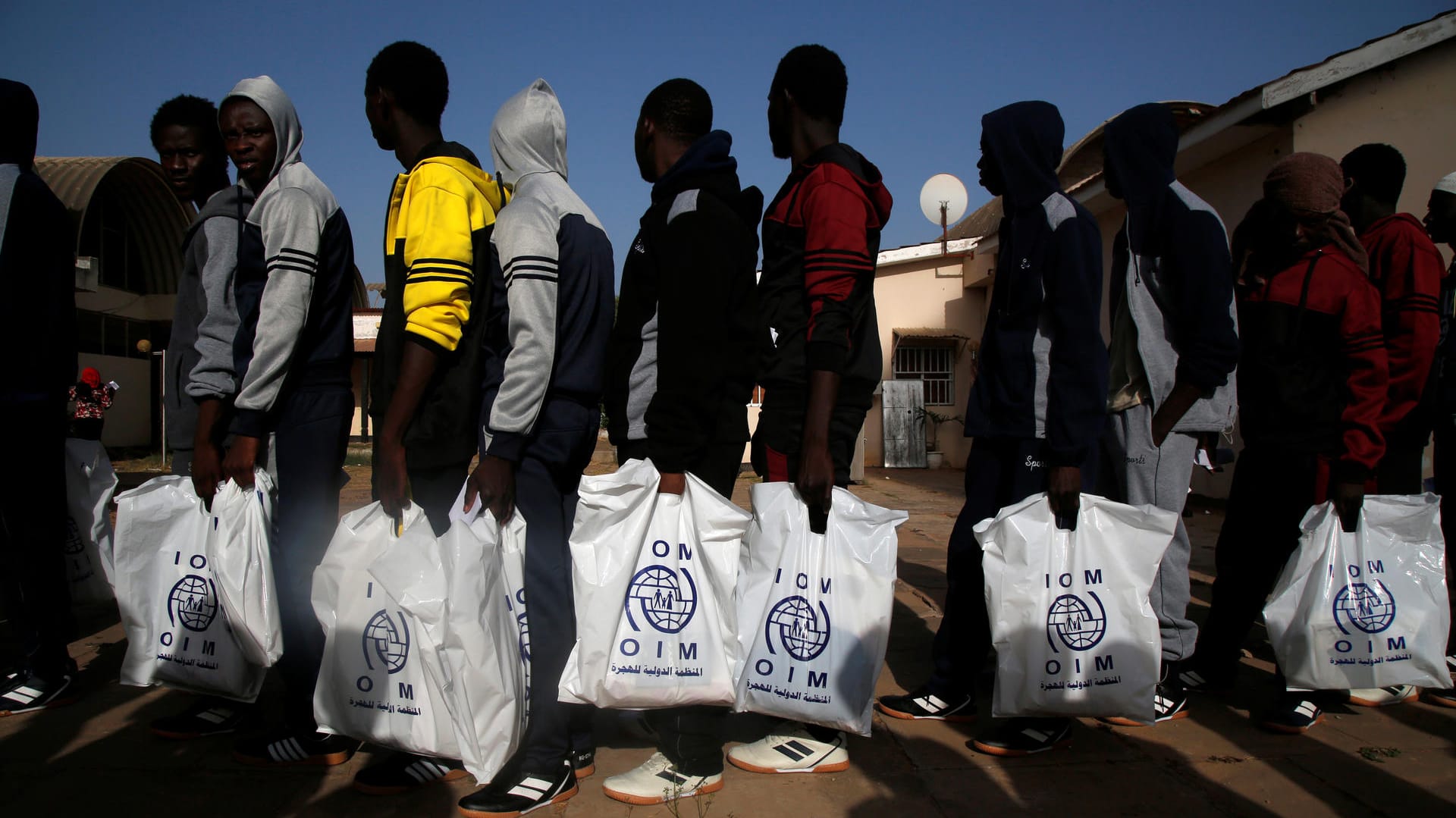 Migranten halten IOM-Tüten in der Hand: In Libyen haben UN-Helfer dabei zusehen müssen, wie ein Mann erschossen wurde. (Archivbild)