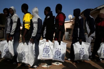 Migranten halten IOM-Tüten in der Hand: In Libyen haben UN-Helfer dabei zusehen müssen, wie ein Mann erschossen wurde. (Archivbild)