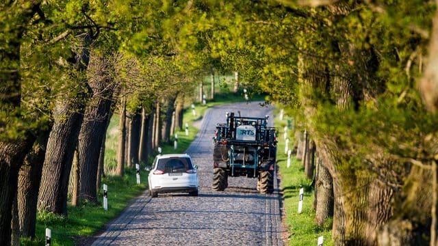 Landwirtschaftliche Fahrzeuge können Erntereste und rutschigen Dreck auf der Fahrbahn hinterlassen.