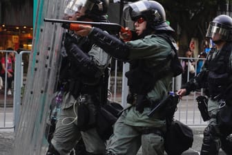 En Polizist in Hongkong richtet seine Waffe auf Demonstranten: In Tuen Mun im Nordwesten der Stadt errichteten Aktivisten Barrikaden.
