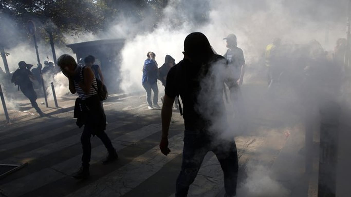 Demonstranten stehen in Paris im Tränengasnebel.