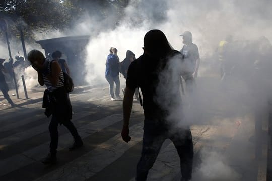 Demonstranten stehen in Paris im Tränengasnebel.