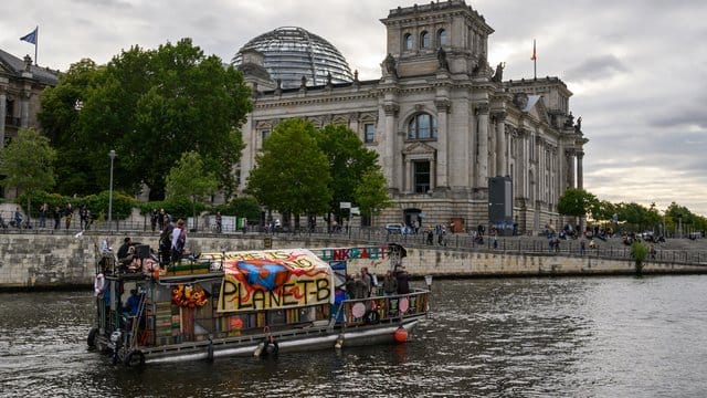 Demonstranten fahren mit einem Boot am Berliner Reichstagsgebäude vorbei. Demonstranten fahren mit einem Boot am Berliner Reichstagsgebäude vorbei.