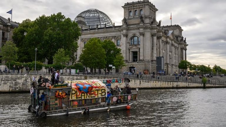 Demonstranten fahren mit einem Boot am Berliner Reichstagsgebäude vorbei.
