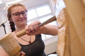 Sophia Böhner erlernt ein traditionelles Handwerk: Mit Bildhauereisen und Klüpfel bearbeitet die angehende Holzbildhauerin ein Objekt.