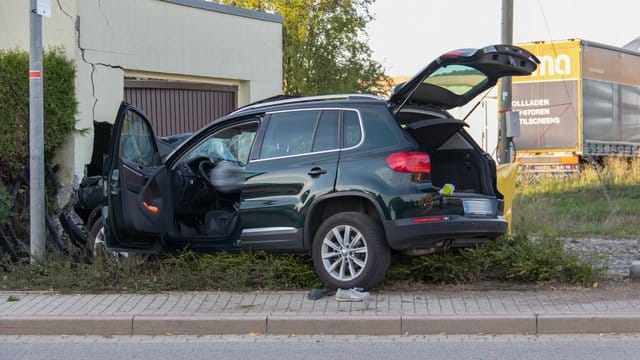Ein beschädigter SUV steht nach einem Unfall vor einer Garage. Ein beschädigter SUV steht nach einem Unfall vor einer Garage.