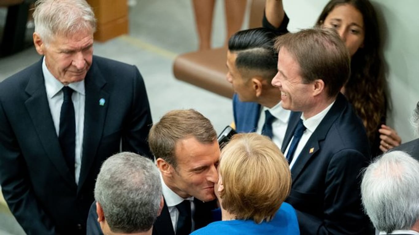 Angela Merkel wird am Rande des UN-Klimagipfels von Emmanuel Macron und Harrison Ford (l) begrüßt.