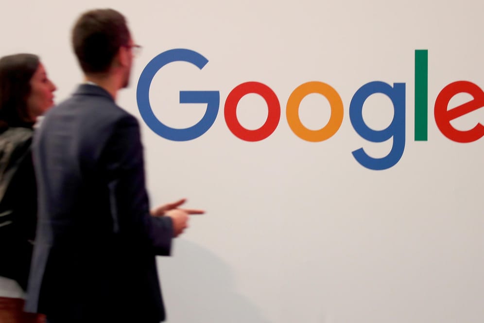 Ein Mann und eine Frau gehen an einer Wand mit dem Google-Logo vorbei: Der Konzern will den Datenschutz bei seinem Sprachassistenten verbessern.