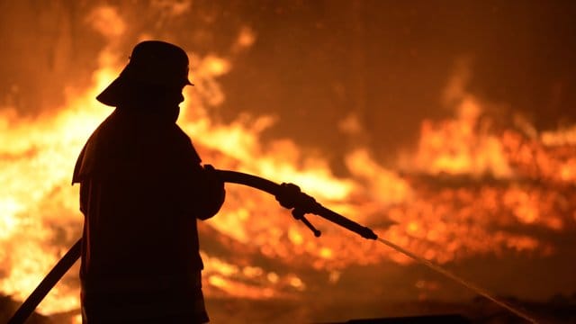 Ein Feuerwehrmann löscht einen Brand. (Symbolbild)