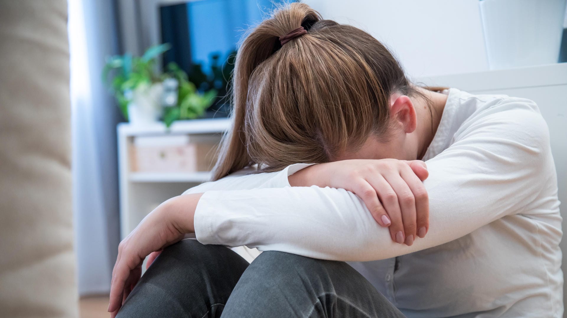 Mädchen sitzt auf dem Boden: Wer eine Fehlfunktion der Schilddrüse hat, kann unter Stimmungsschwankungen leiden.