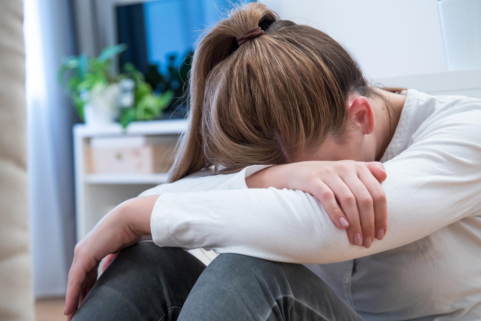 Mädchen sitzt auf dem Boden: Wer eine Fehlfunktion der Schilddrüse hat, kann unter Stimmungsschwankungen leiden.