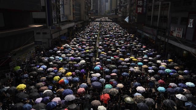 Anhänger der Demokratiebewegung ziehen mit Regenschirmen durch Hongkong. Anhänger der Demokratiebewegung ziehen mit Regenschirmen durch Hongkong.