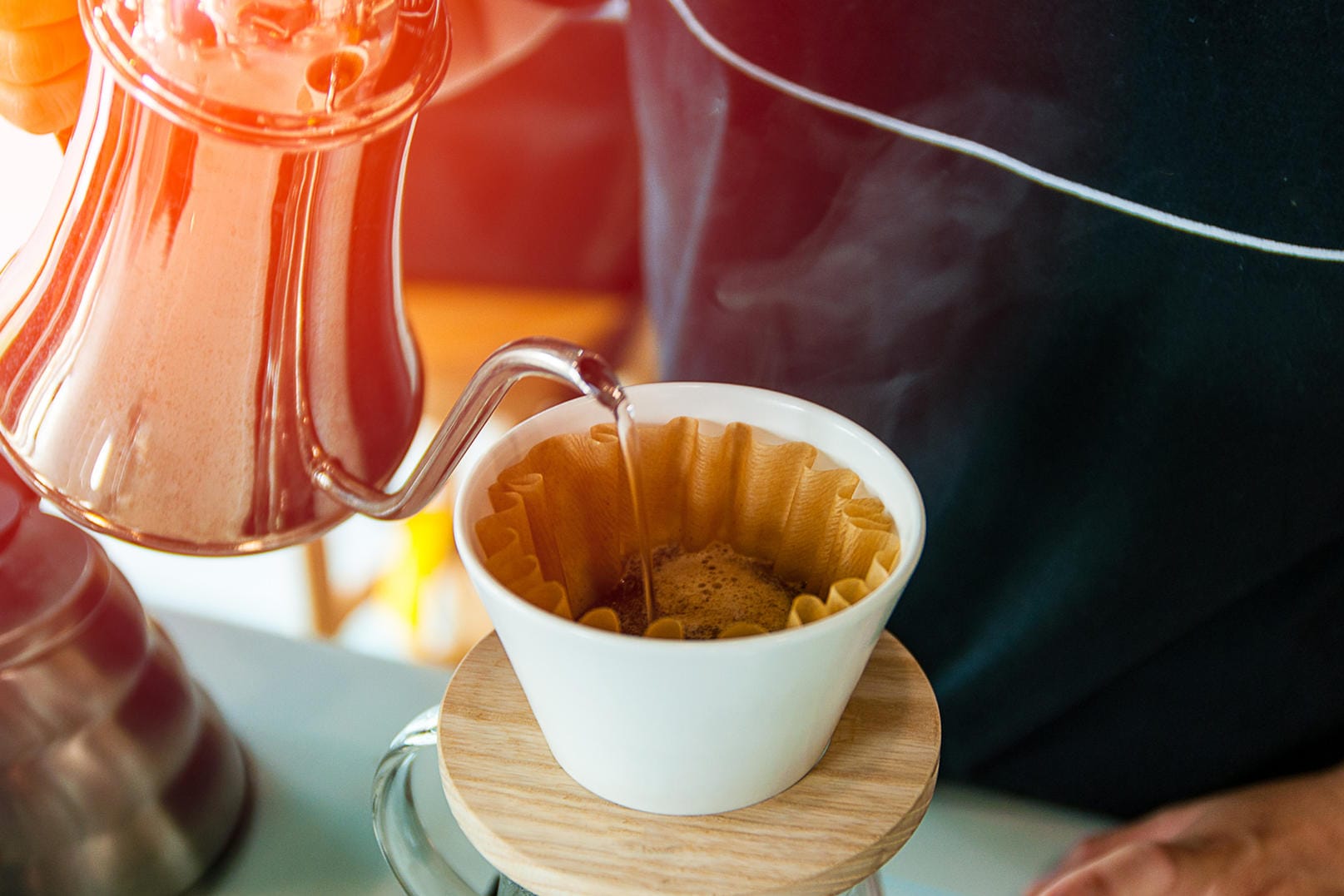 Ein Mann gießt Kaffee auf: Nach dem Quellen wird der Slow Coffee mit heißem Wasser aufgebrüht.