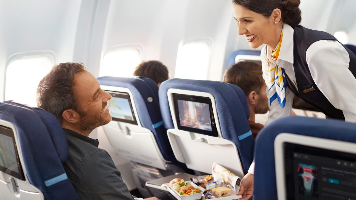 Fluggast und Stewardess in der Premium Economy Class: Viele Reisende empfinden das größere Platzangebot als Vorteil.