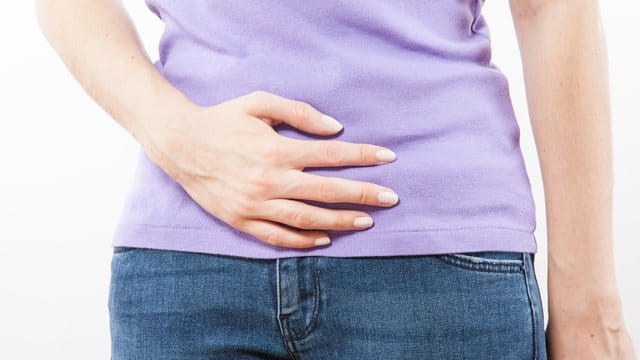 Eine Frau hält sich den Bauch: Ständiger Harndrang kann unter anderem auch durch eine Stoffwechselerkrankung wie Diabetes ausgelöst werden.