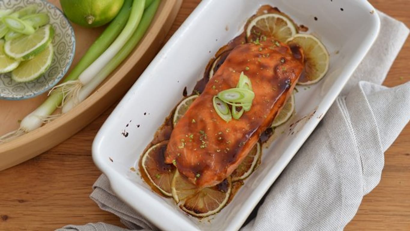 Der Lachs wird mit der japanischen Teriyaki-Sauce glasiert und auf einem Limettenbett 10 Minuten im Ofen gebacken.