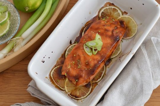 Der Lachs wird mit der japanischen Teriyaki-Sauce glasiert und auf einem Limettenbett 10 Minuten im Ofen gebacken.