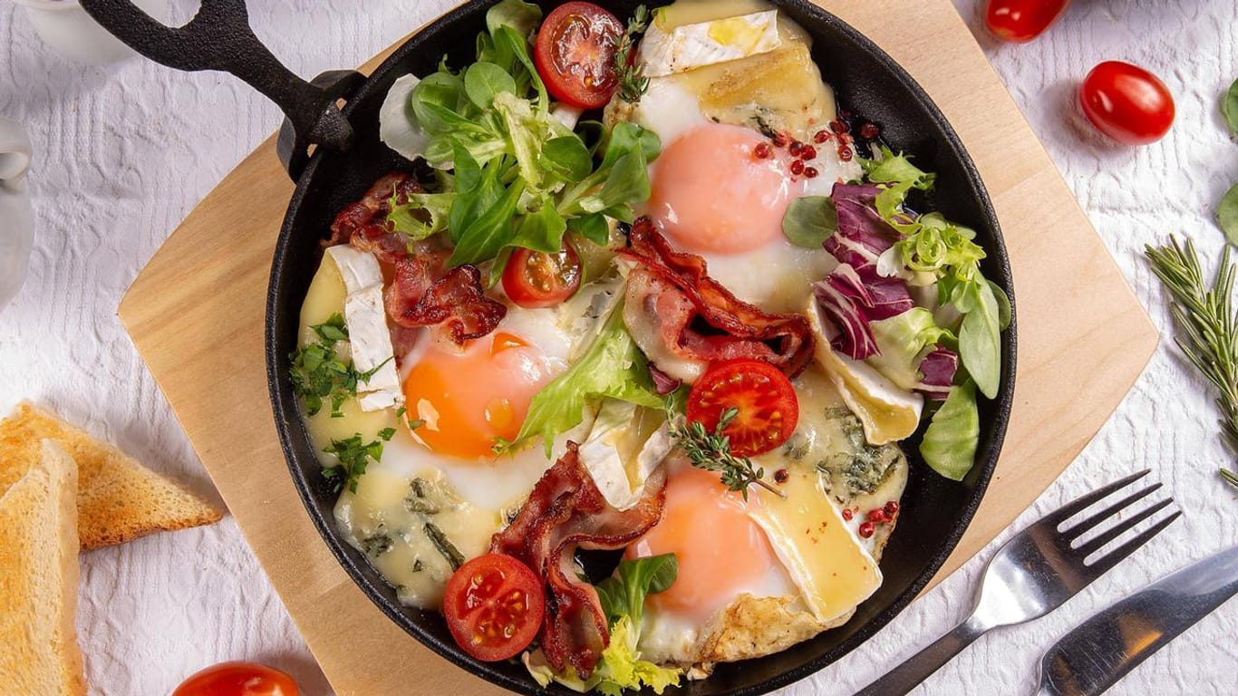 Spiegeleier in einer Pfanne mit Gemüse und Käse: Mit einem leckeren Frühstück lässt es sich viel besser in den Tag starten.