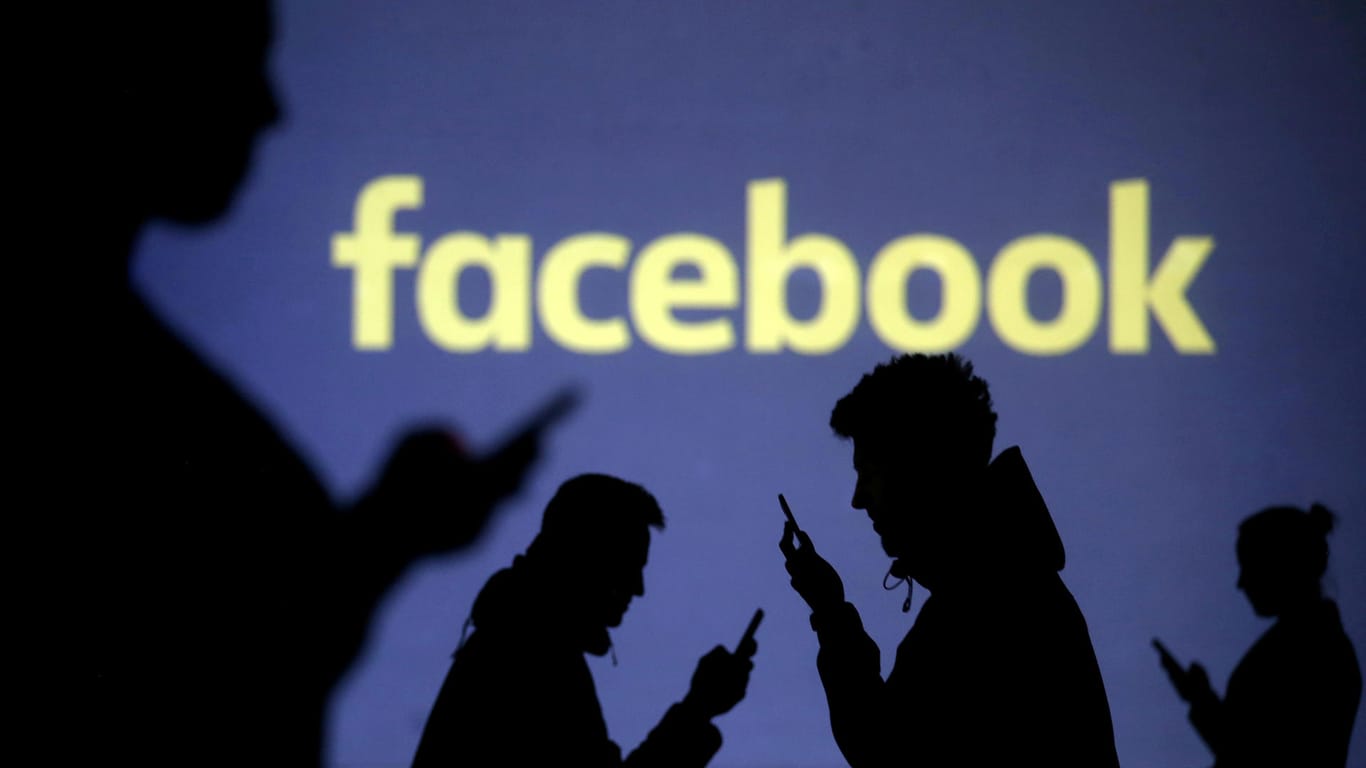 Menschen vor dem Facebook-Logo: Das soziale Netzwerk will Aussagen von Politiker zulassen, auch wenn sie gegen die Regeln verstoßen.