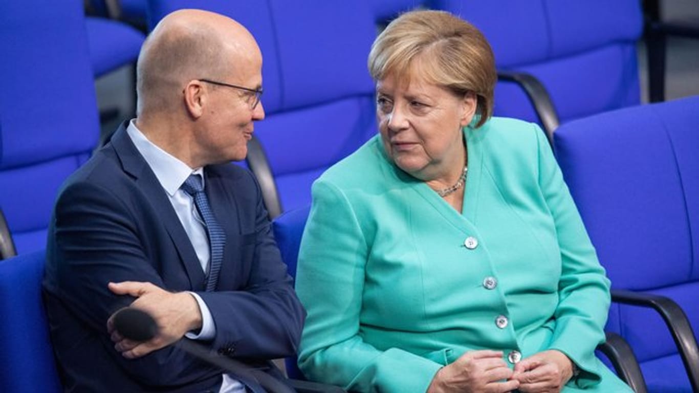 Unionsfraktionschef Ralph Brinkhaus und Kanzlerin Angela Merkel sprechen im Bundestag miteinander.