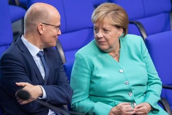 Unionsfraktionschef Ralph Brinkhaus und Kanzlerin Angela Merkel sprechen im Bundestag miteinander.