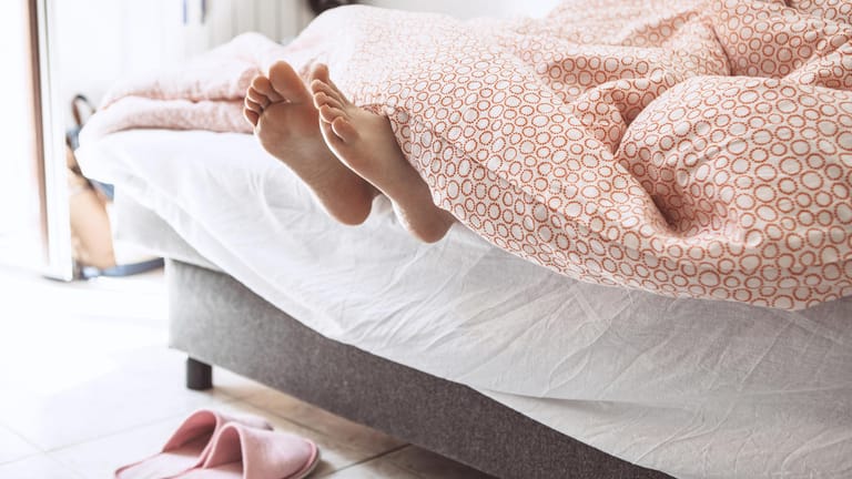 Füße schauen unter einer Bettdecke hervor: Die Stiftung Warentest hat Bettdecken getestet, die besonders warm halten sollen.