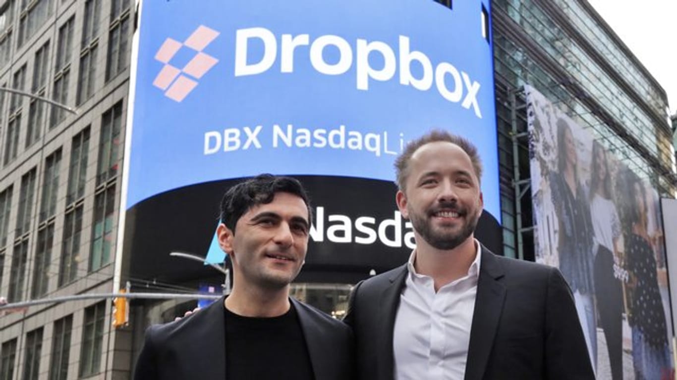 Arash Ferdowsi (l) und Drew Houston, Gründer des Online-Speicherdienstes Dropbox, stehen vor einem Plakat zum Börsengang ihres Unternehmens.